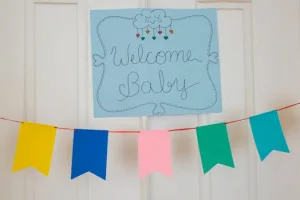 Cheerful baby shower decorations with colorful banner and welcome sign displayed indoors.